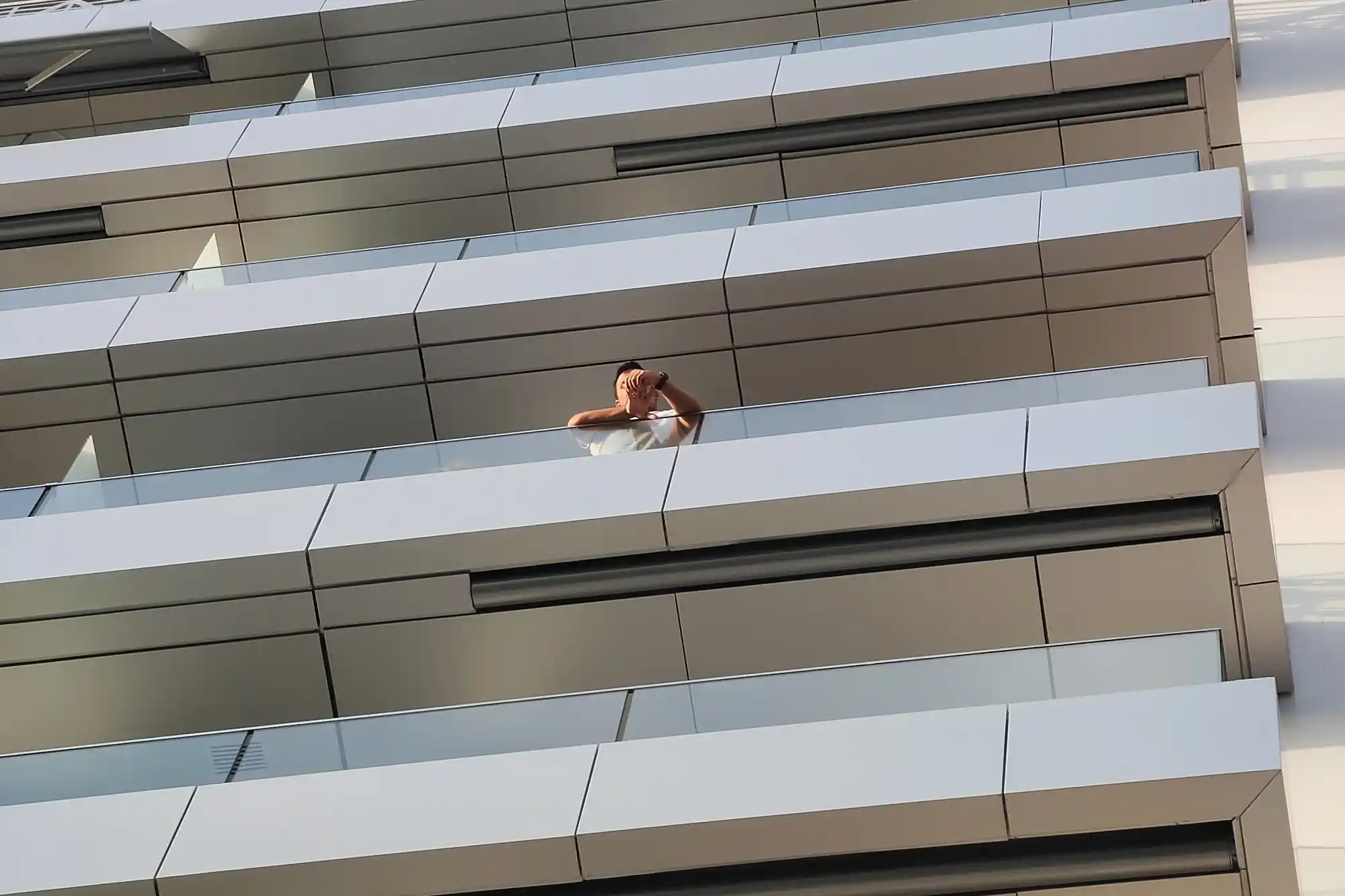 Man looking over a modern balcony of a high rise