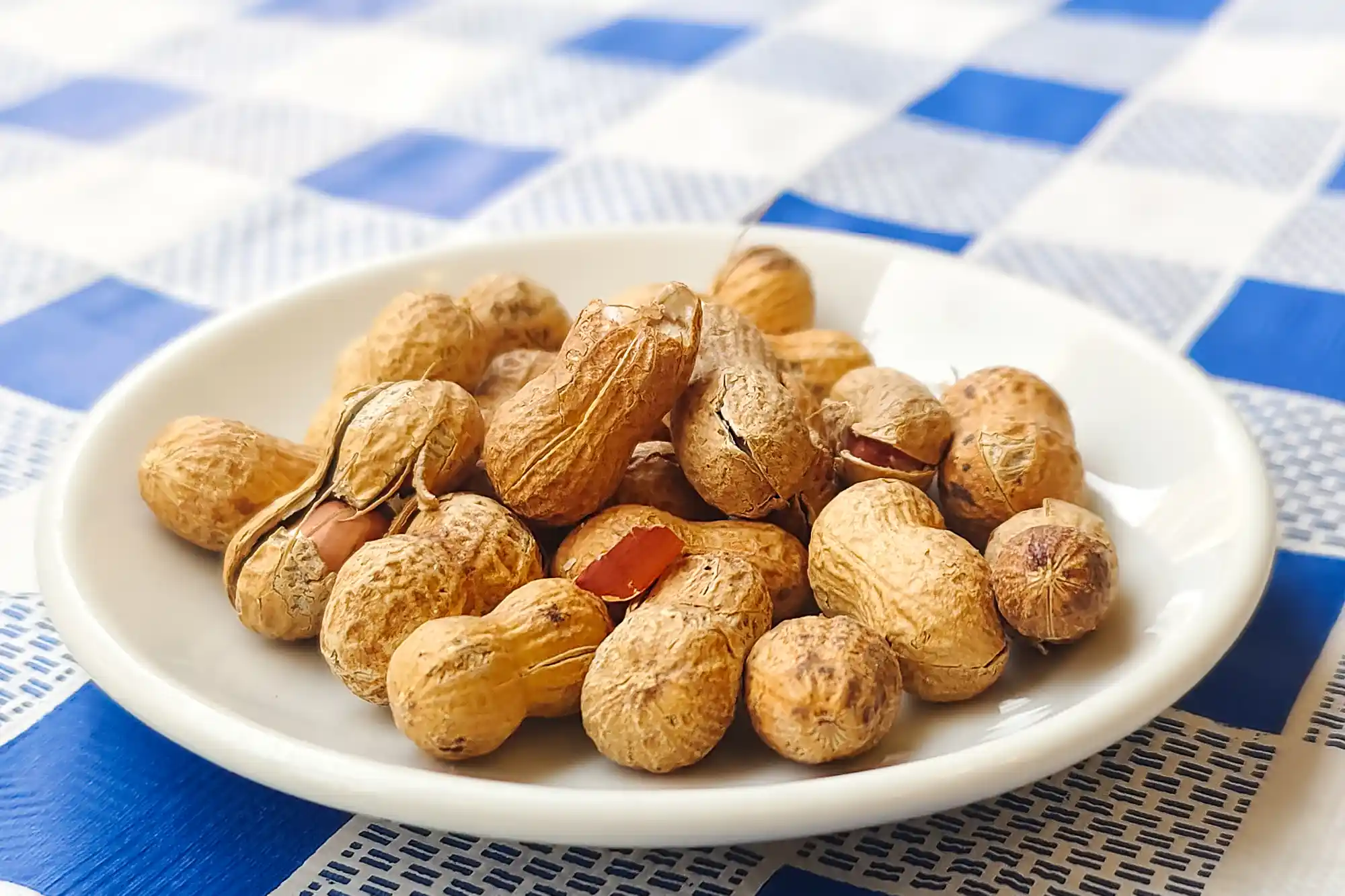 A plate of Valencian peanuts on a blue and white checkered paper table cloth