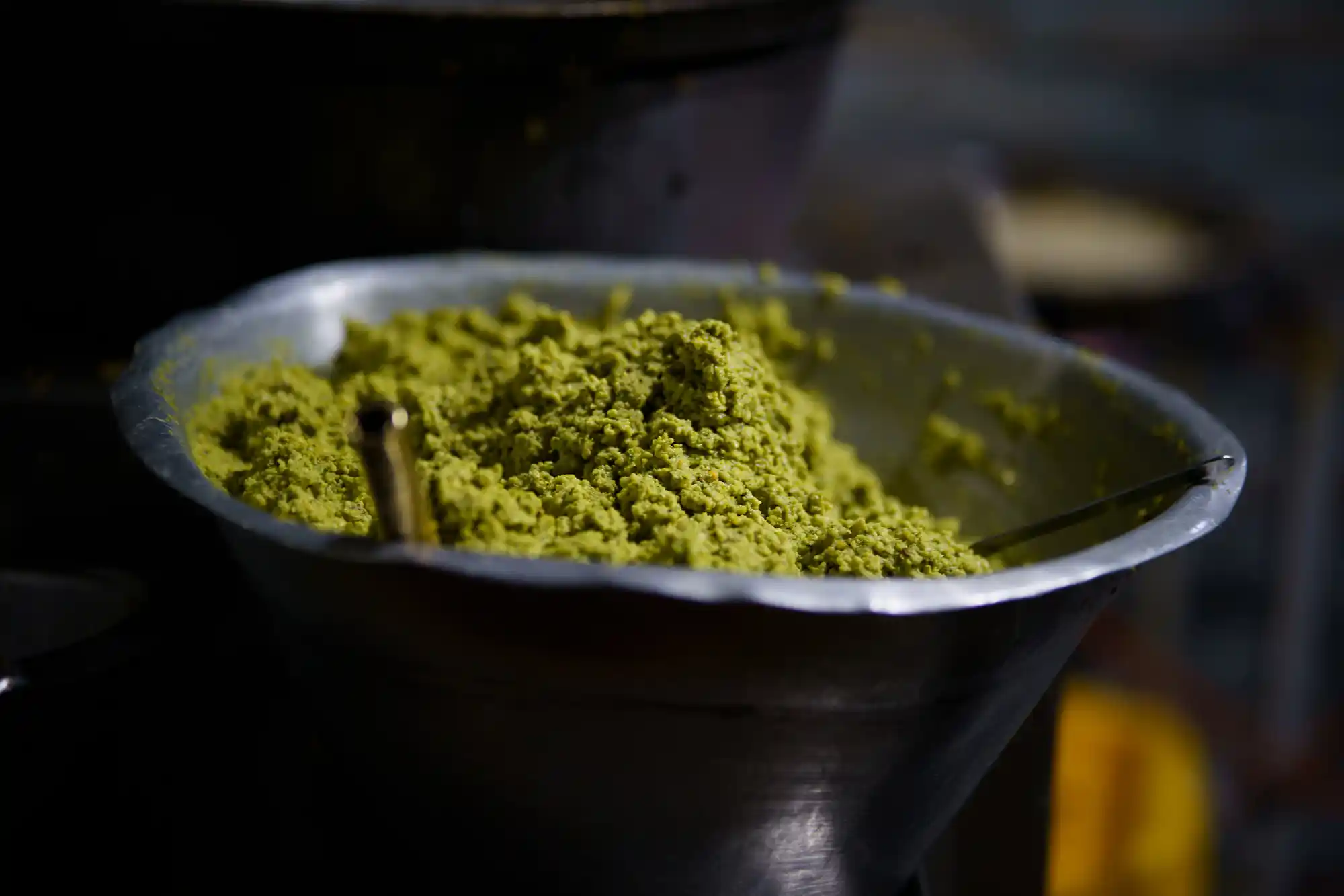 Green falafel mix in a metal bowl at a Luxor street food stand, waiting to be shaped into patties and fried.