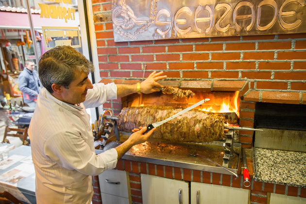 Kebap horizontal real flame with man cutting the meat
