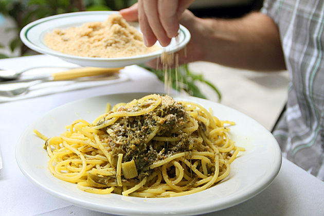 Pasta con le Sarde at Ristorante Amato in Palermo - man putting cheese on pasta.