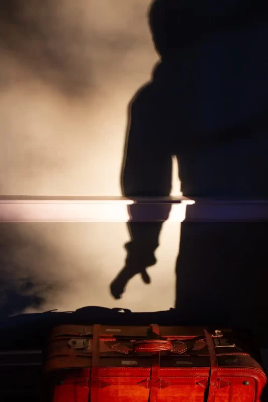 Memory of a shadow of a man picking up a real suitcase